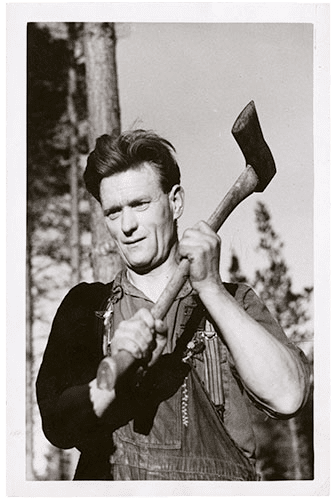 A clean-shaven man in overalls and shirt sleeves raises an axe over his left shoulder.